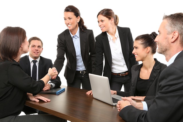 Team of property managers in suits meeting with two people shaking hands across a conference table
