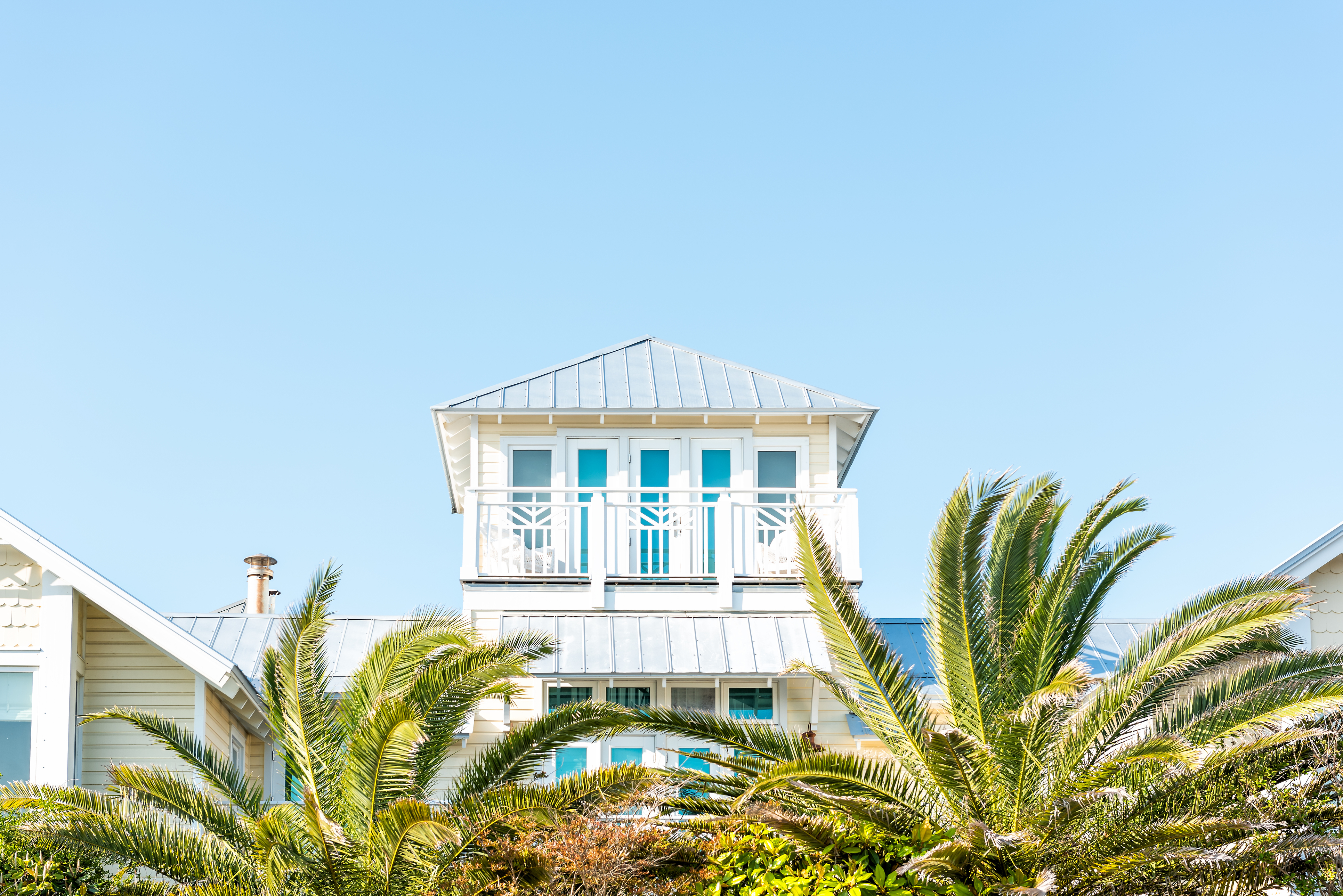 An exterior view of the top floor of a house with leafy trees obstructing the view of the floor below it