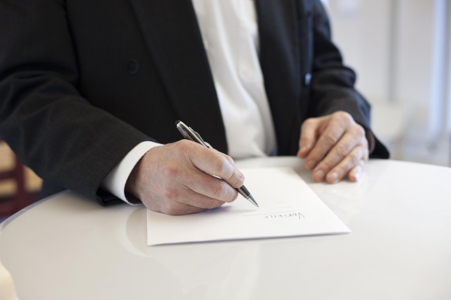 Person in a suit signing a contract on a white table